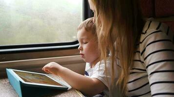 madre Guardando sua figlio giocando gioco su tampone nel il treno video