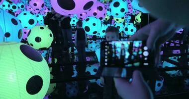 Taking photo of child in Infinity Mirror room with dotted balls by Yayoi Kusama video