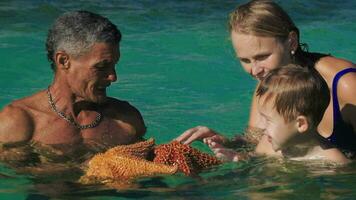 Man showing tourists two big starfish video