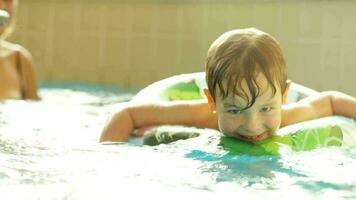 Happy little boy swimming with rubber ring in the pool video