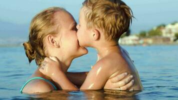 Boy kissing and embracing mother in sea video