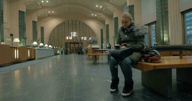 Woman waiting in station hall and using smart phone video