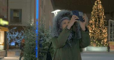 donna assunzione cellula scatti nel il strada con Natale illuminazione video