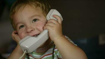 opgewonden weinig jongen pratend over- telefoon ontvanger video