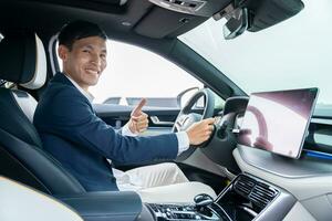 Happy businessman driving car before buying new electric vehicle with thumbs up. Electric car. EV Car. EV vehicle. photo