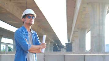 Professional engineer worker in protective helmet and blueprints paper on hand inspecting construction project a road expressway that is done at construction site. photo