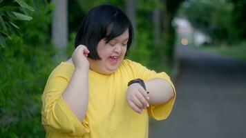 mirando a el reloj, un asiático niña con abajo síndrome se regocija.como yo ejercitado en el parque. foto