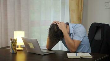 Asian young freelande touching his head on table in home after bad news business failure or get fired and feeling discourage. photo