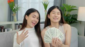 Happy two Asian young women are showing dollars and showing thumbs up. Online business success consept. photo