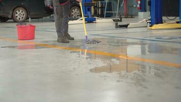 Worker man clean dirty floor in car-care center. photo