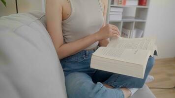 cerca arriba mano joven mujer leyendo libro en sofá a hogar. foto