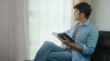 freelance asian man sitting in home and reading a book. photo