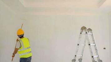 Asian construction worker uses roller to paint the ceiling at the construction site . photo