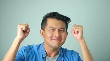 A successful handsome asian man dancing, enjoying party, pointing fingers up and having fun, standing over white background. photo
