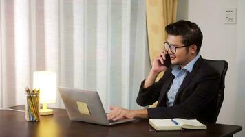 Asian businessman working on using phone and laptop computer at home office,working at home on the Internet. photo