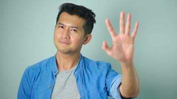 Asian man standing white background doing stop palm of the hand. warning expression with negative and serious gesture on the face. photo