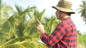 Young Asian farmer using tablet and checking his coconut. Technology for Smart farmer concept. photo