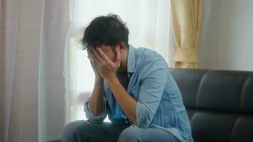 Asian young freelande touching his head on table in home after bad news business failure or get fired and feeling discourage. photo