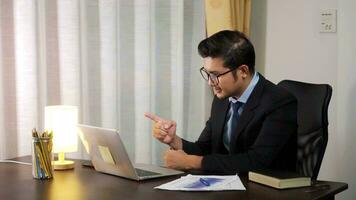 Asian businessman working on laptop computer at home office desk talk on online communication video call with employee, boss,webcam view, working at home on the Internet. photo