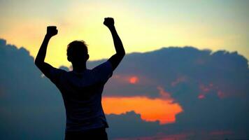 Silhouette of young millionaire reaching a new goal, happiness, business success . On the cityscape at sunrise urban city view. photo