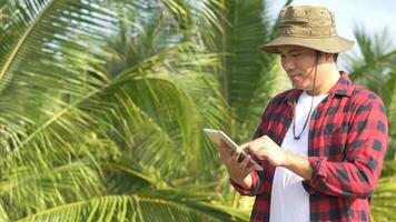 Young Asian farmer using tablet and checking his coconut. Technology for Smart farmer concept. photo
