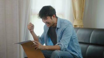 Asian man receives happy news in the mail. In the home. photo