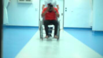 borroso escena vídeo ángulo ver de hospital personal, silla de ruedas ese paciente sentado en él. foto