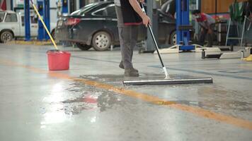 Worker man clean dirty floor in car-care center. photo