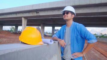 Asian civil engineer using laptop and blueprint is inspecting construction project a road expressway that is done at construction site. photo