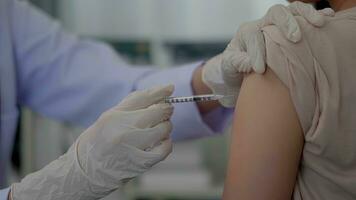 Close up hand asian woman doctor injecting in arm of asian girl. photo