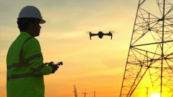 silueta de eléctrico ingeniero forzando un zumbido a inspeccionar alto voltaje polos durante el puesta de sol tiempo. foto