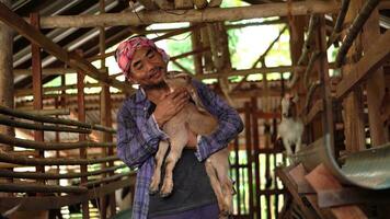 A farm worker or a farm owner raising young goats in a farmhouse. photo