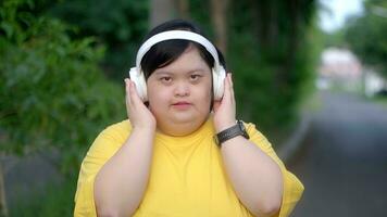 Down syndrome girl exercising in the park wearing headphones. photo