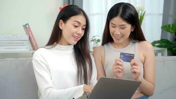 Two asian smiling women in showing credit card. Online business success . photo