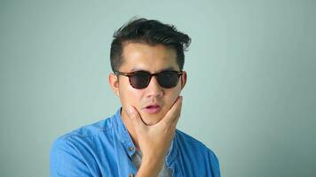 Asian man handsome wearing sunglasses gesture thumb up white background. photo