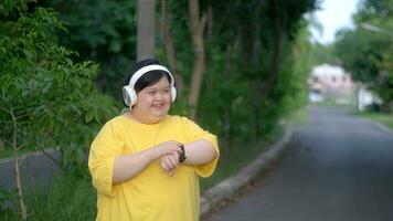 Down syndrome watching the clock and headphones while exercising at the park. photo