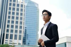 Asia young businesman with laptop , tall building background ,Generative AI. photo