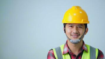 Asian young engineer wearing a yellow safety goggles and safety vest. looking to the side and smiling. photo