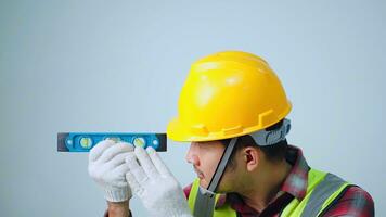 un joven ingeniero vistiendo un amarillo seguridad. utilizando agua nivel medición regla en vacío Copiar espacio. foto