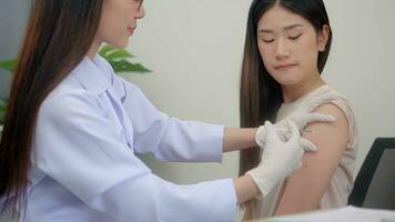 hermosa asiático mujer médico inyectando en brazo de asiático muchacha. foto
