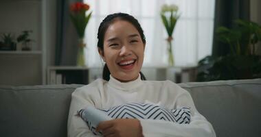 Happy young Asian woman watching a movie on television while sitting on the sofa photo