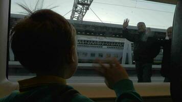 Child in train waving hand to grandparents as he leaving video