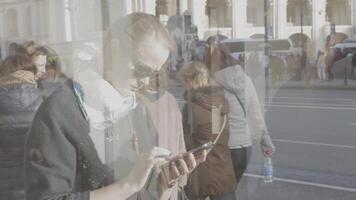 in een zonnig dag Aan de straat in de reflectie van de vitrine gezien jong meisje wie werken Aan mobiel telefoon video