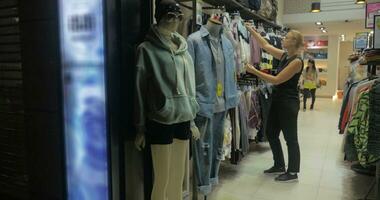 rubio mujer sonriente mientras elegir blusas en el comercio, hong kong, China video