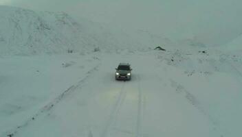 coche en cubierto de nieve la carretera en montañas, pájaro ojo ver video