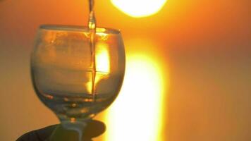 Gießen Wasser in Glas beim Sonnenuntergang video