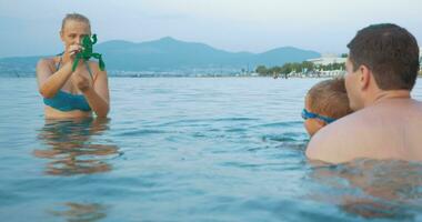 Family playing with toy frog in the sea video