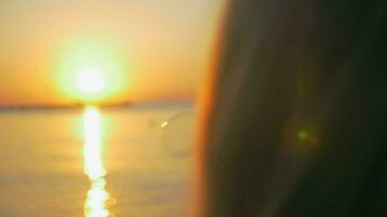 fille soufflant bulles à bord de mer pendant le coucher du soleil video