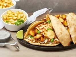 Side view Shawarma with fried Potatoes on board Cookware Chicken Roll photo