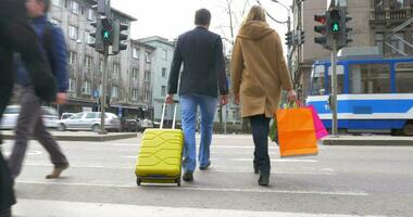 Couple with suitcase and shopping bags crossing the road video